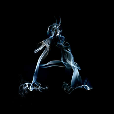 one letter from a smoky alphabet isolated on blackの写真素材