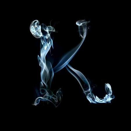one letter from a smoky alphabet isolated on blackの写真素材