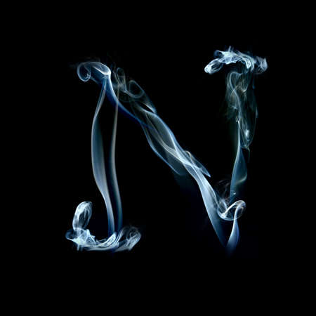 one letter from a smoky alphabet isolated on blackの写真素材