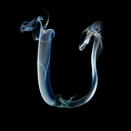 one letter from a smoky alphabet isolated on blackの写真素材