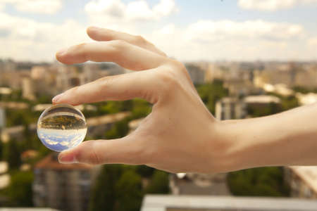 a little glass ball in a hand under the cityの写真素材