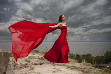 woman in red dress with red scarf before the stormの写真素材