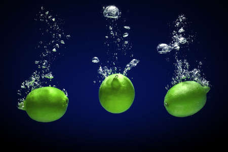 Fresh lime dropped into water with bubblesの写真素材