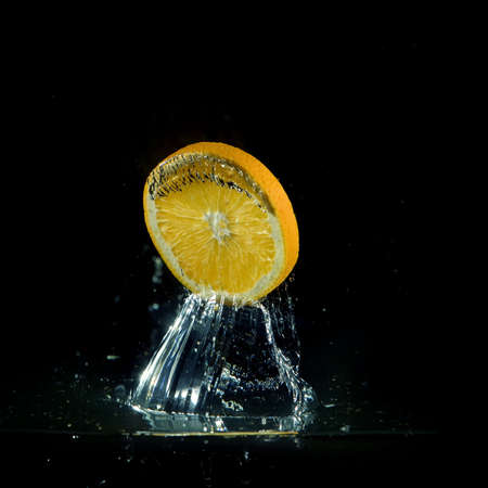 orange splashing out of water on black backgroundの写真素材