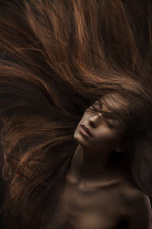 beautiful woman with long hair on dark backgroundの写真素材