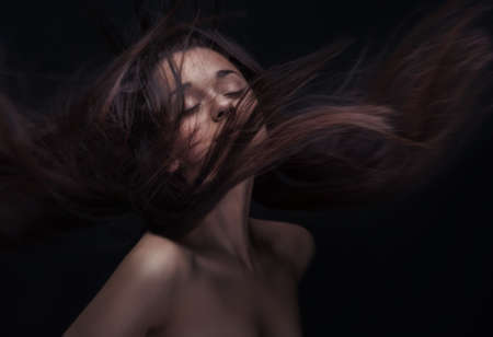 young brunette woman with long flying hairの写真素材