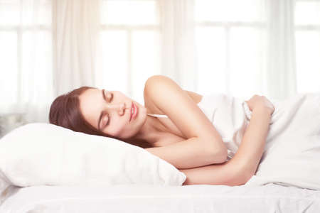 Beautiful woman lying down in bedの写真素材