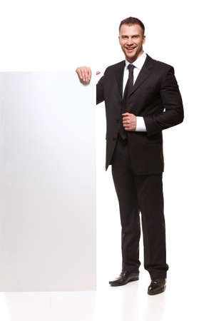 Portrait of happy smiling young business man with blank signboard isolated on white backgroundの写真素材