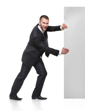 Portrait of happy smiling young business man pushing blank signboard isolated on white backgroundの写真素材