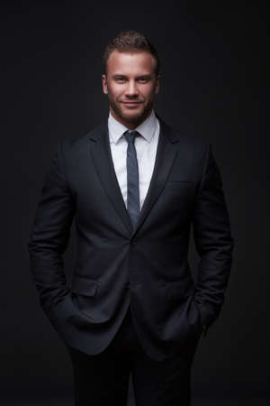Portrait of young businessman isolated on dark backgroundの写真素材