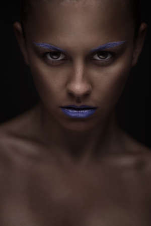 closeup portrait of beautiful young woman with creative makeup and hairstyle on dark backgroundの写真素材