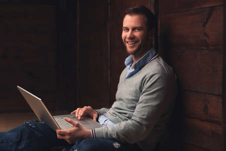 Portrait of a young handsome man with laptop in urban background