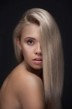 Portrait of beautiful blond women with long hair posing on dark backgroundの写真素材