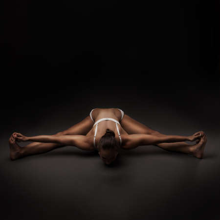studio shoot of healthy latino woman doing yoga over dark backgroundの写真素材