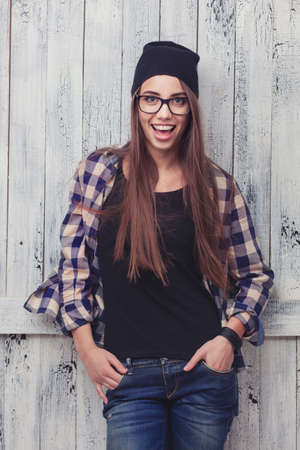 Hipster girl in glasses and black beanie on the wooden backgroundの写真素材
