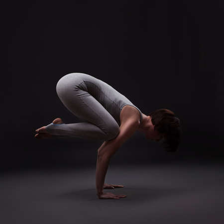 young beautiful woman yoga posing on a black studio backgroundの写真素材