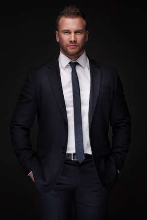 Portrait of young businessman isolated on dark backgroundの写真素材