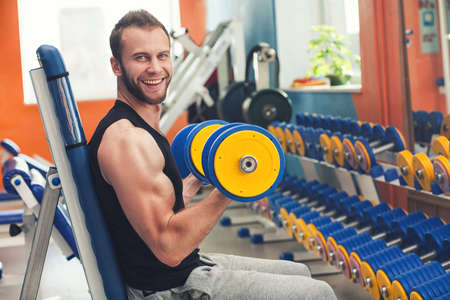 Young smiling athlete lifting weights in the gymの写真素材