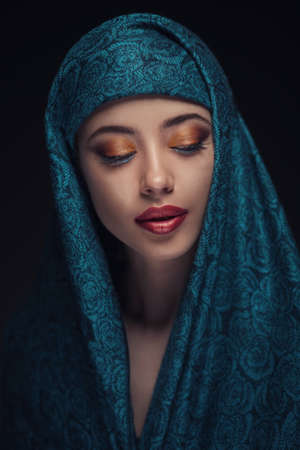 Portrait of a beautiful woman with arabian makeup in paranja isolated on dark backgroundの写真素材