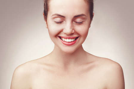 Close up portrait of beautiful young happy smiling woman wiht closed eyes, isolated over light grey backgroundの写真素材