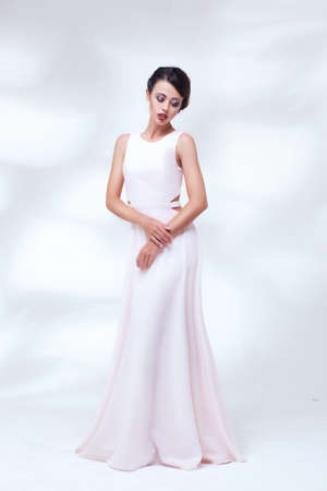 portrait of beauty woman in white dress on light studio backgroundの写真素材