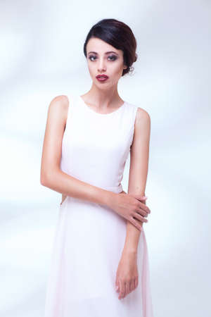 portrait of beauty woman in white dress isolated over light blue studio backgroundの写真素材