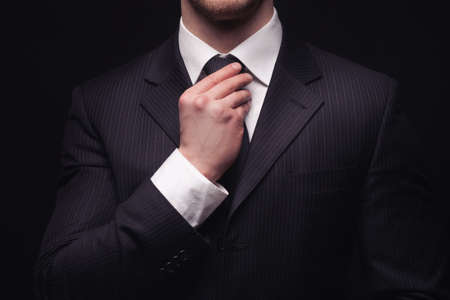 Portrait of young businessmans suit isolated on dark backgroundの写真素材