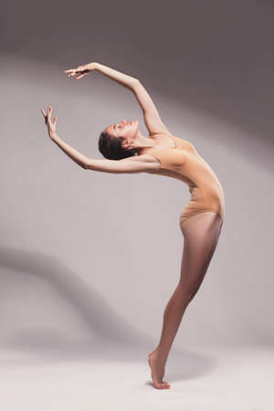 silhouette of young beautiful dancer in beige swimsuit on  studio backgroundの写真素材