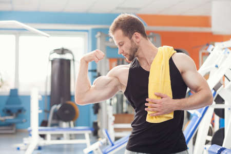 young man near weight training equipment in sport gymの写真素材