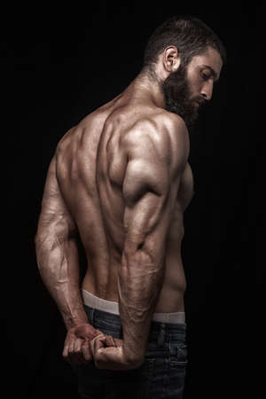 strong athletic beardy mans back isolated over black background