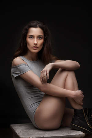 studio portrait of beautiful sexy woman in grey swimsuit posing on dark backgroundの写真素材