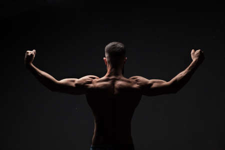 strong athletic mans back on dark grey gradient backgroundの写真素材