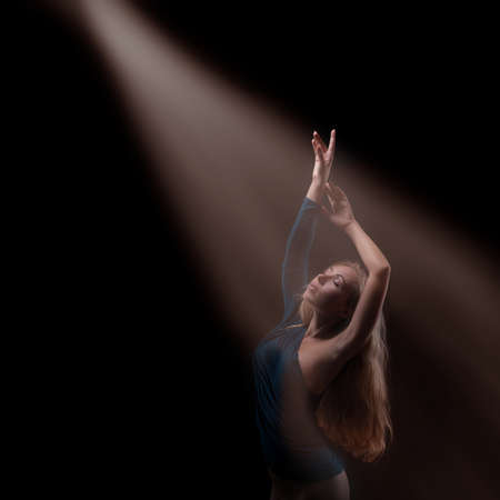 Sexy beautiful woman with long blond hair posing in blue dress. looking at magnificent light.の写真素材