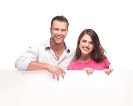 Portrait of a happy couple holding a blank billboard on white backgroundの写真素材