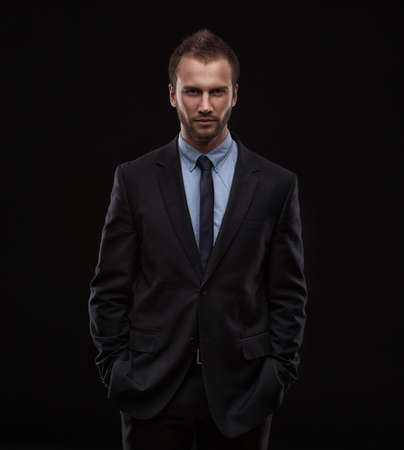 Portrait of young businessman isolated on dark backgroundの写真素材