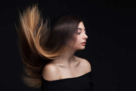closeup studio portrait of attractive young woman with long brown hair over dark studio backgroundの写真素材