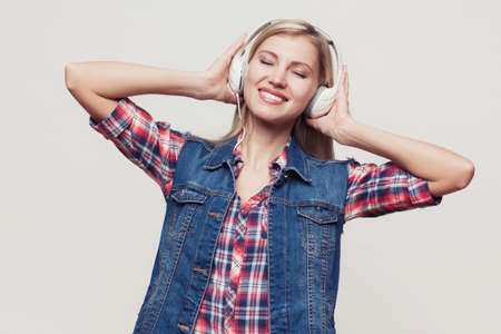 Closeup fashion studio portrait of hipster young smiling woman in black hat and denim vest over...