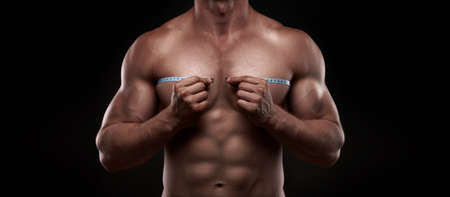 bodybuilder with a measuring tape around his chestの写真素材