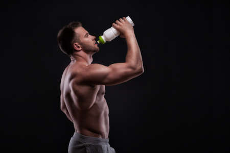 Muscular guy drinking water after trainingの写真素材