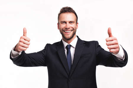 Studio portrait of young handsome businessman showing thumbs up gesture isolated on white backgroundの写真素材