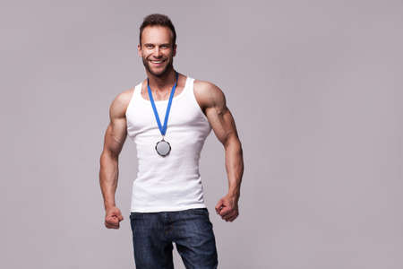 Portrait of athletic man in white undershirt with champions medalの写真素材