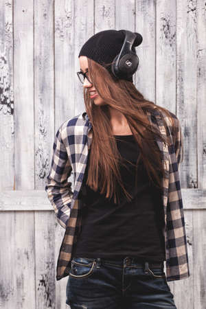 Hipster girl in glasses, headphones and black beanieの写真素材
