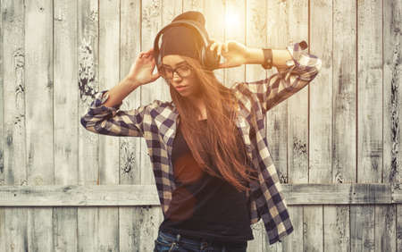 Hipster girl in glasses, headphones and black beanieの写真素材