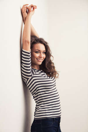 happy brunette woman with curly hair and perfect smile posingの写真素材