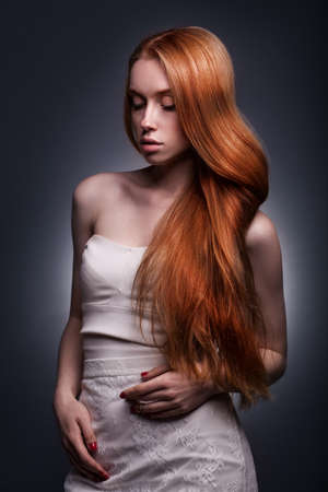 beautiful elegant redhaired woman in a white dressの写真素材