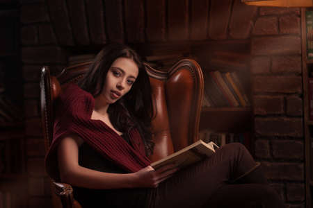 Woman resting with a book near fireplaceの写真素材