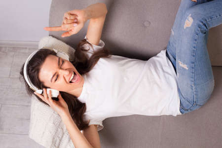 beautiful happy young woman lying on a sofa and enjoying music