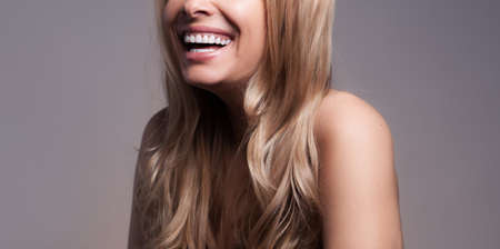 Adult beautiful blond woman with white veneers on the teeth.の写真素材