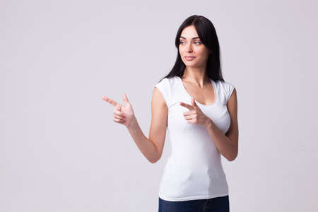 Beautiful brunette woman portrait points with her arms to the sideの写真素材