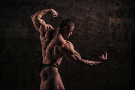 Sporty and healthy muscular man from back on dark grunge backgroundの写真素材